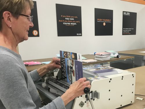 woman hole punching paper in bindery shop